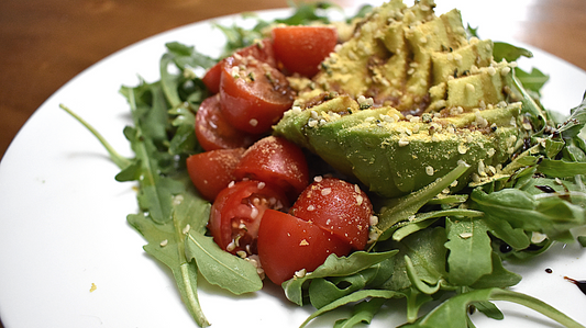 superfood arugula salad with quinoa, avocado, tomato, balsamic, hemp and nutritional yeast