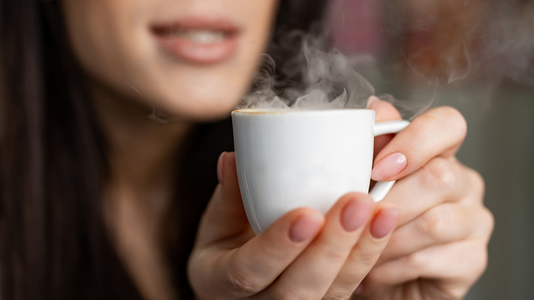 closeup of woman with plump attractive lips holding coffee in her hands